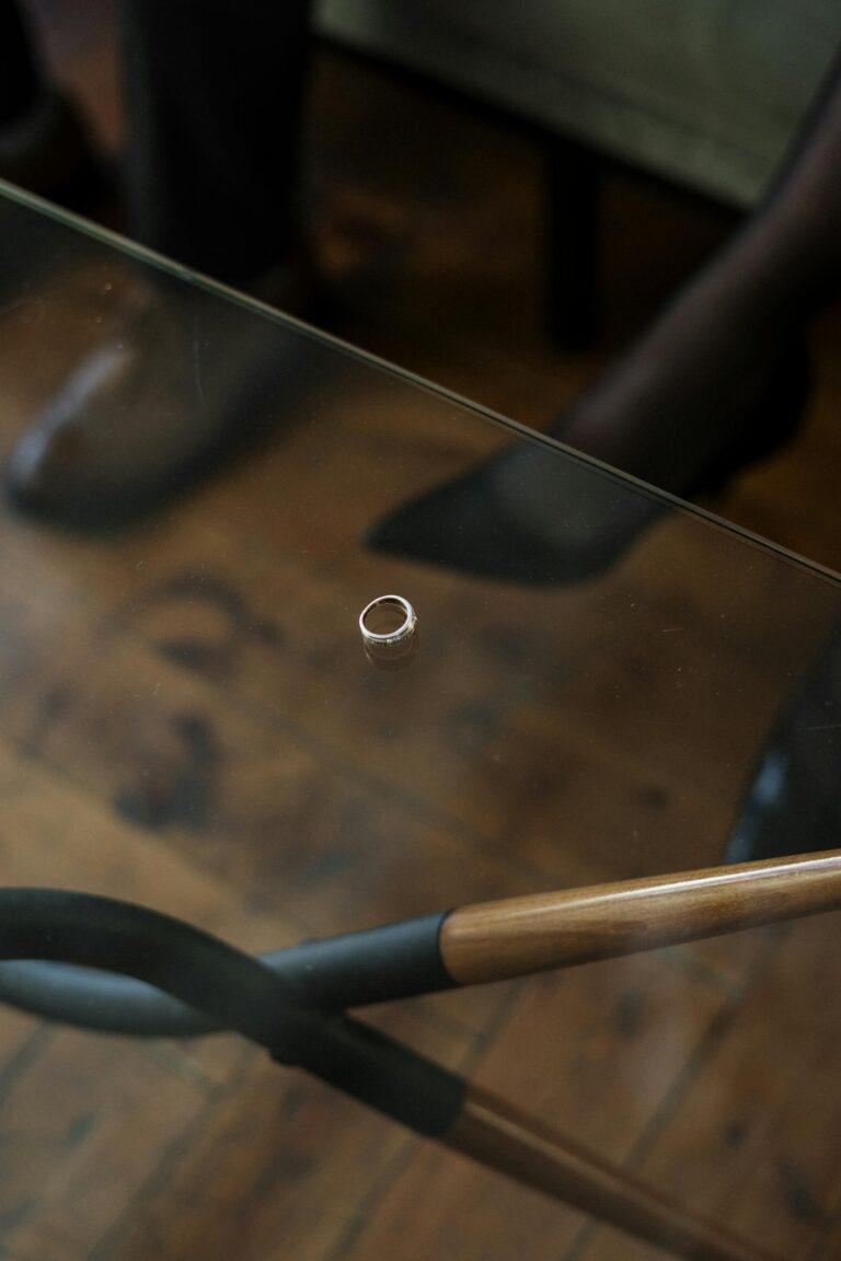 Wedding ring on glass table hints at relationship challenges and separation.