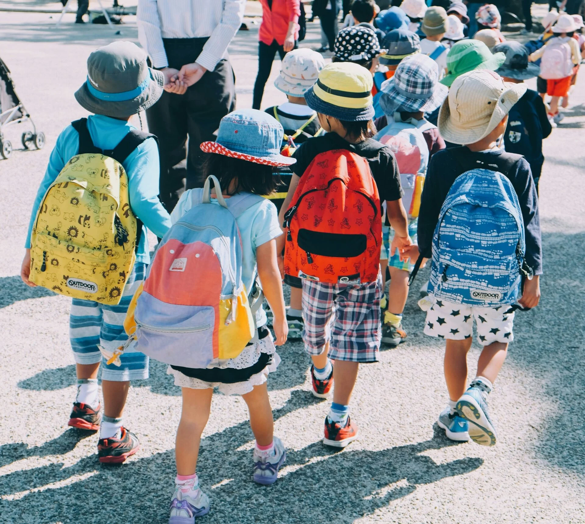 Children walking into school on the first day of the new school year with backpacks.