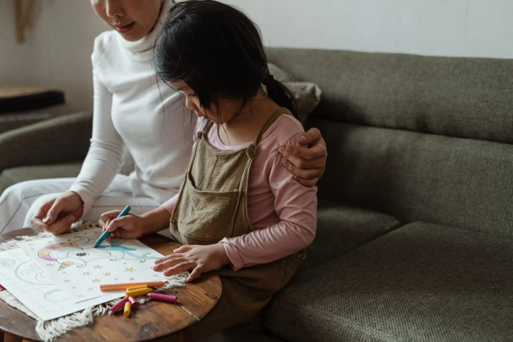 Asian mother coloring with her child at home while spending quality time together.