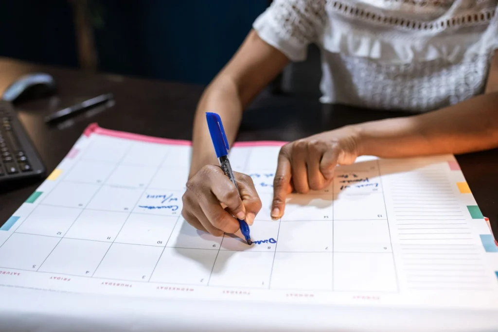 Child marking school events on a family calendar to prepare for the new school year and co-parenting schedule.